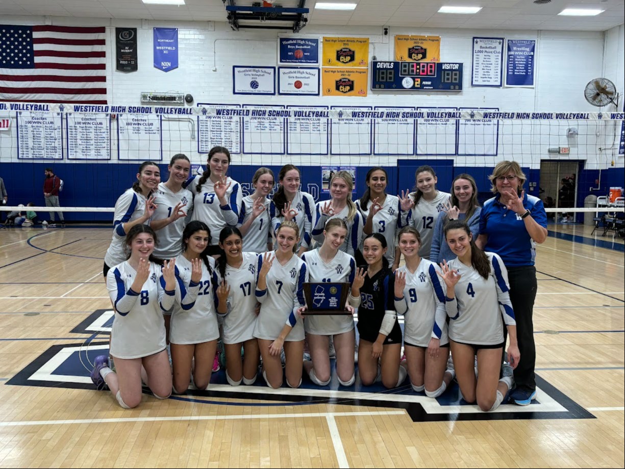 Girls on a volleyball court holding a trophy