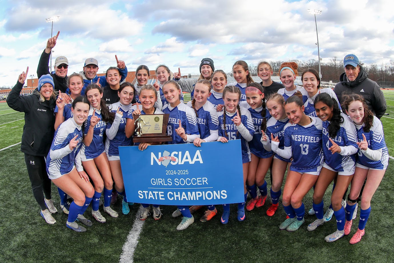 girls on a soccer field holding a trophy
