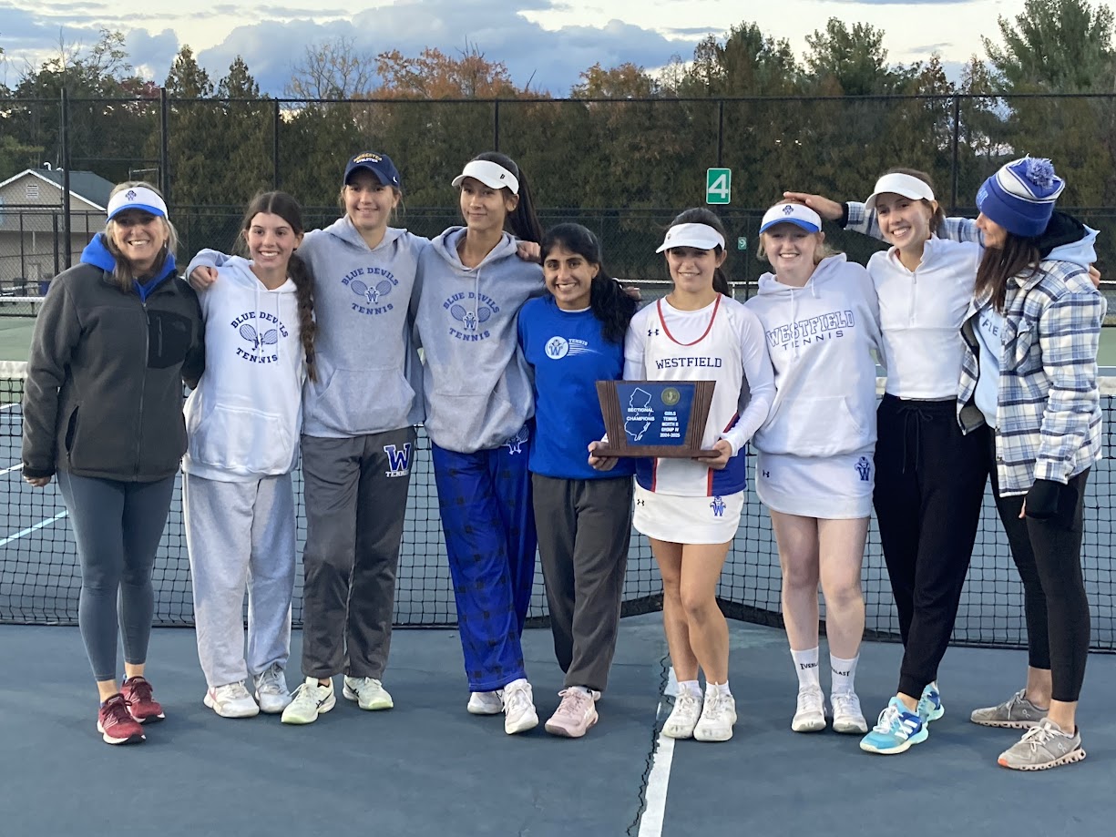 Girls on a tennis court holding a trophy