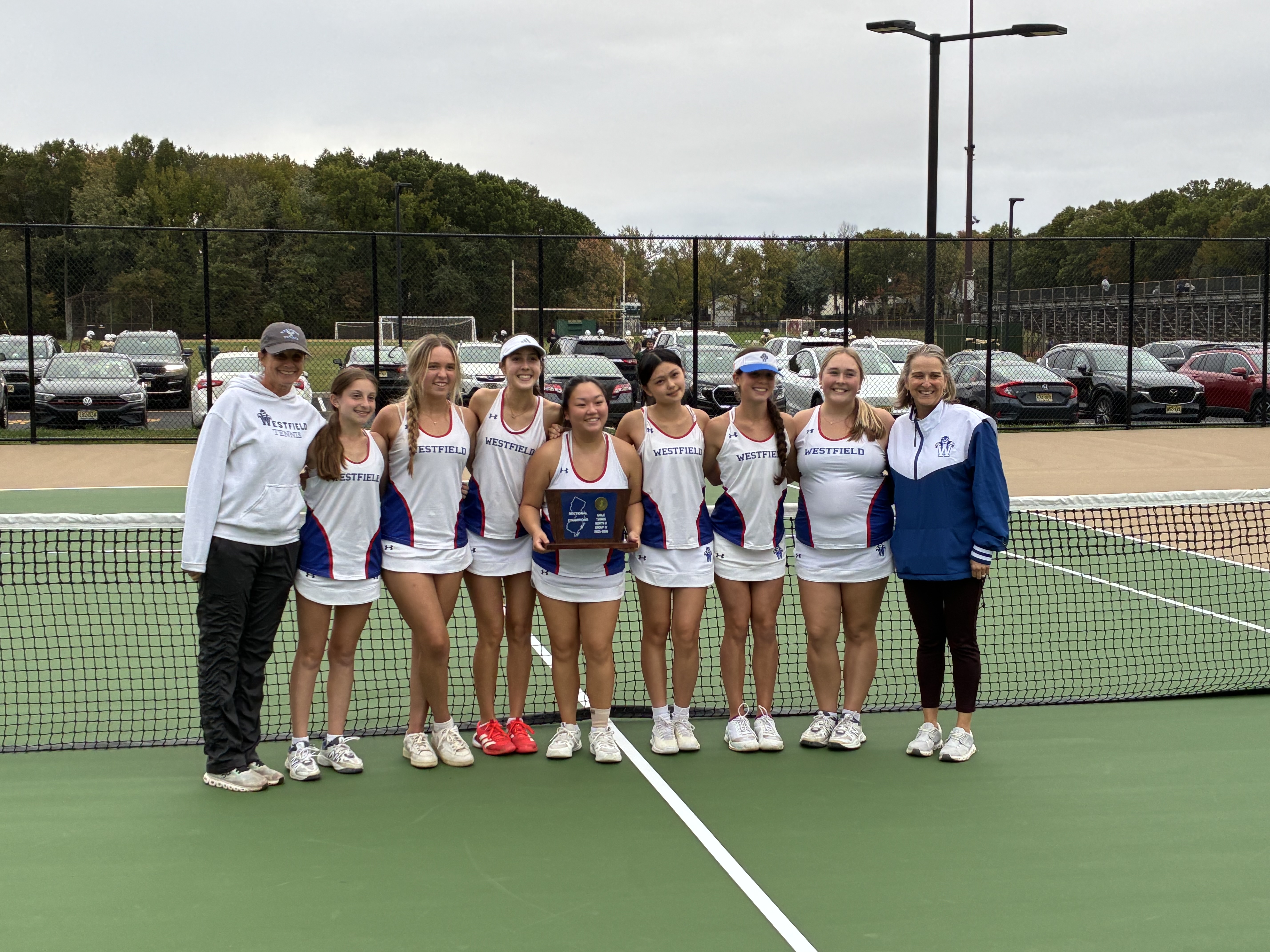 Girls on a tennis court holding a trophy
