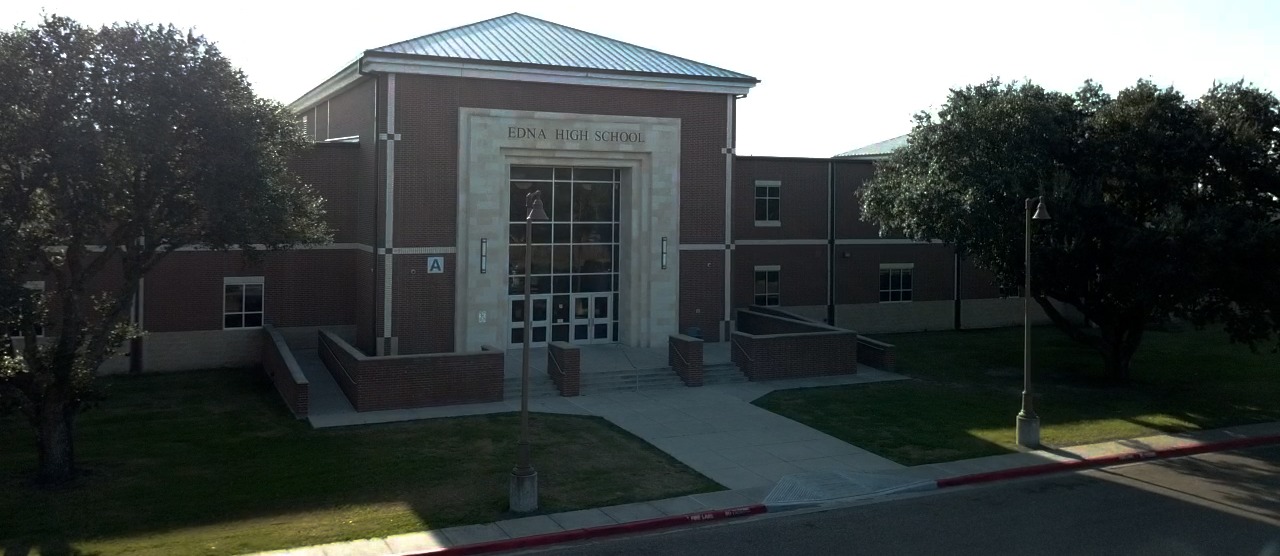 Front view of Edna High School in Edna, TX, showcasing a large building with a prominent front door and multiple windows.