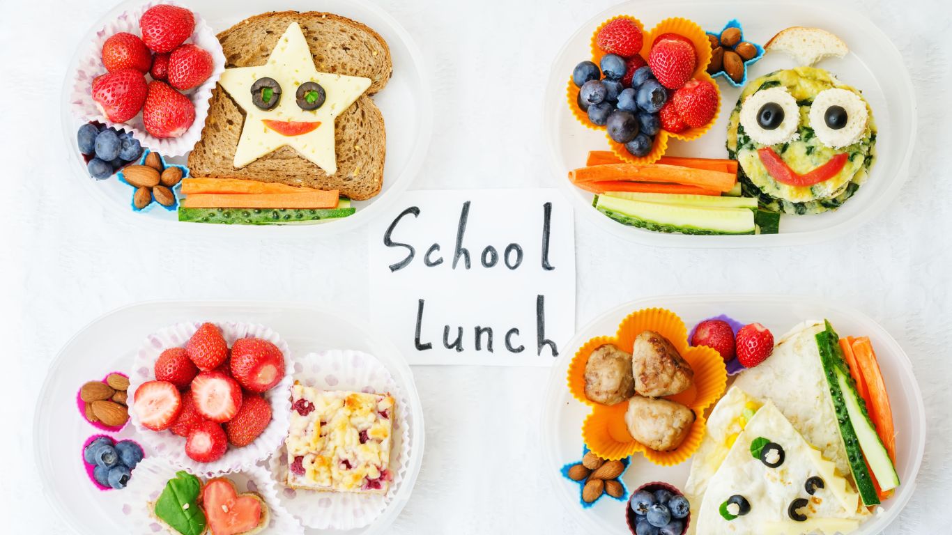 An assortment of creatively arranged school lunches featuring sandwiches, fruits, and vegetables, with the words 'School Lunch' written in the center.