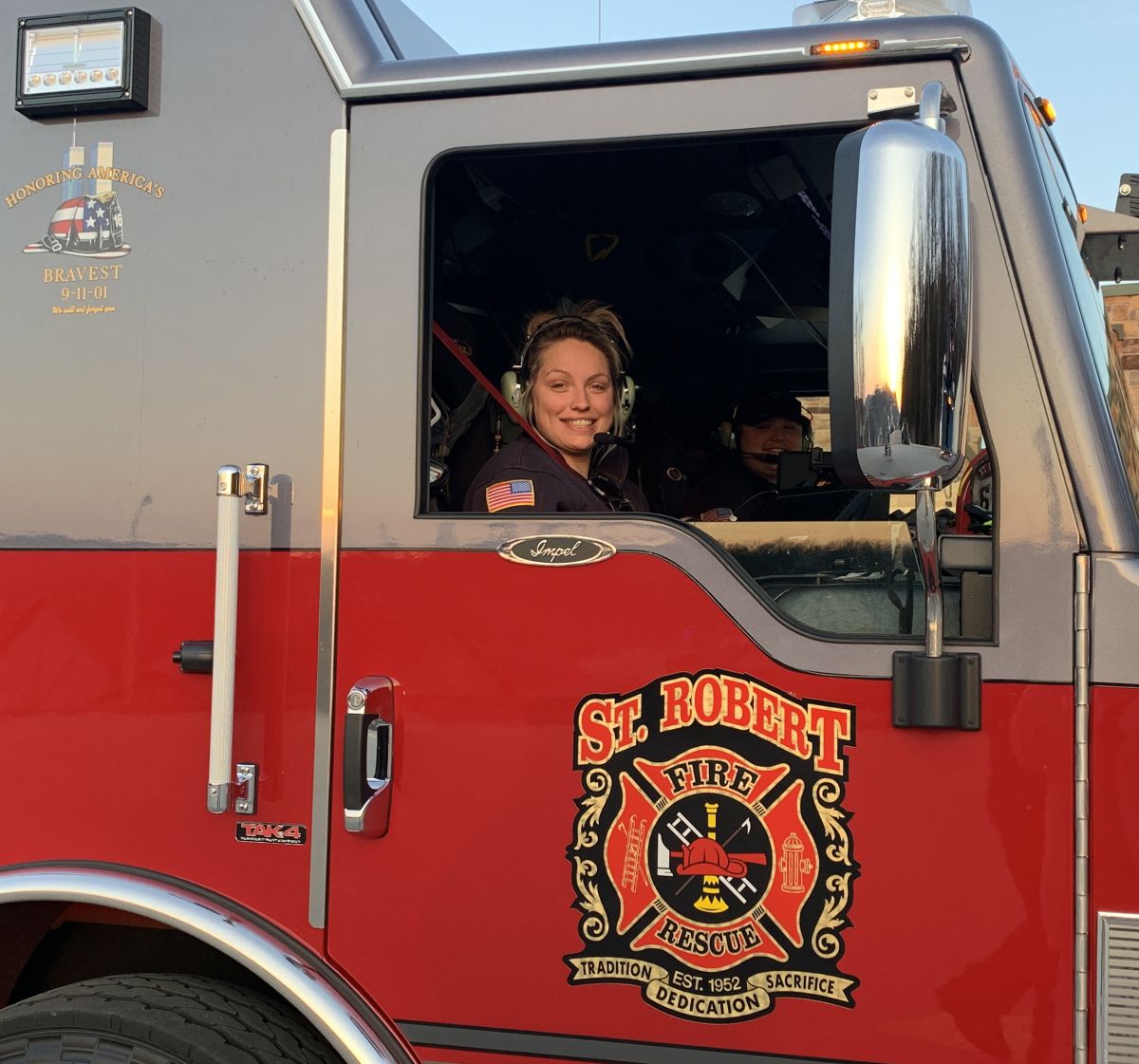 A woman is in the driver's seat of a fire truck