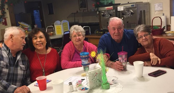 A cheerful group of older adults gathered around a table, enjoying conversation and sharing smiles together.