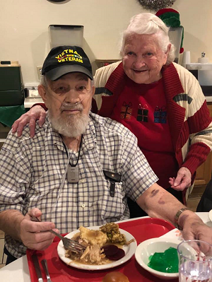 An older couple enjoying a meal together at a cozy table, sharing smiles and delicious food.