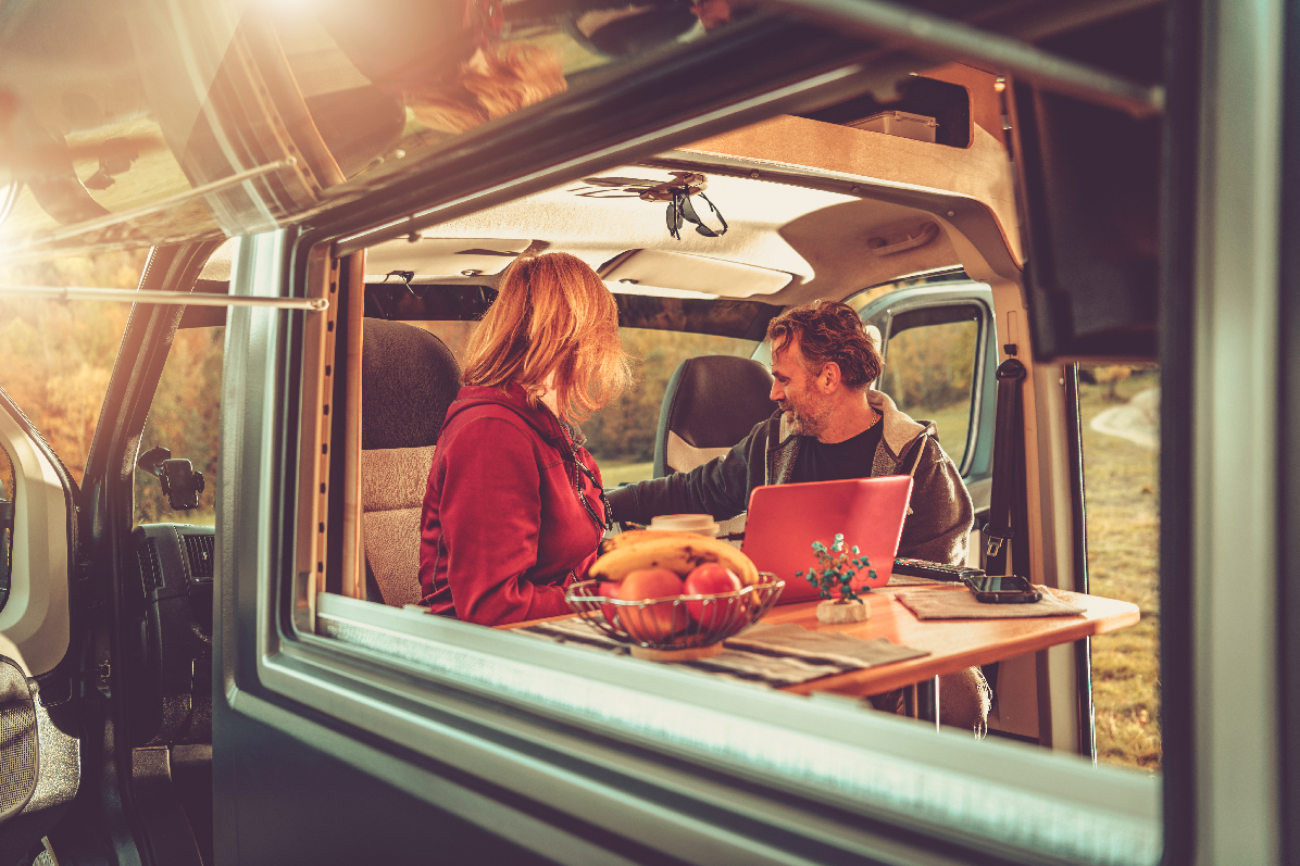 A couple relaxes together in the cozy back of a camper van