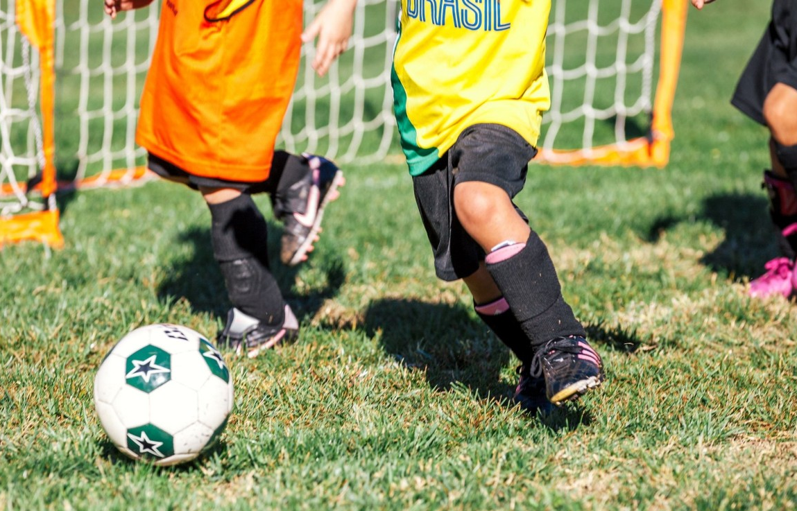  A young boy joyfully kicks a soccer ball on a grassy field