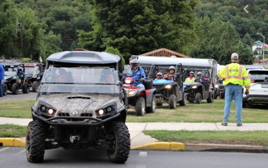 A group of people poses in front of several ATVs