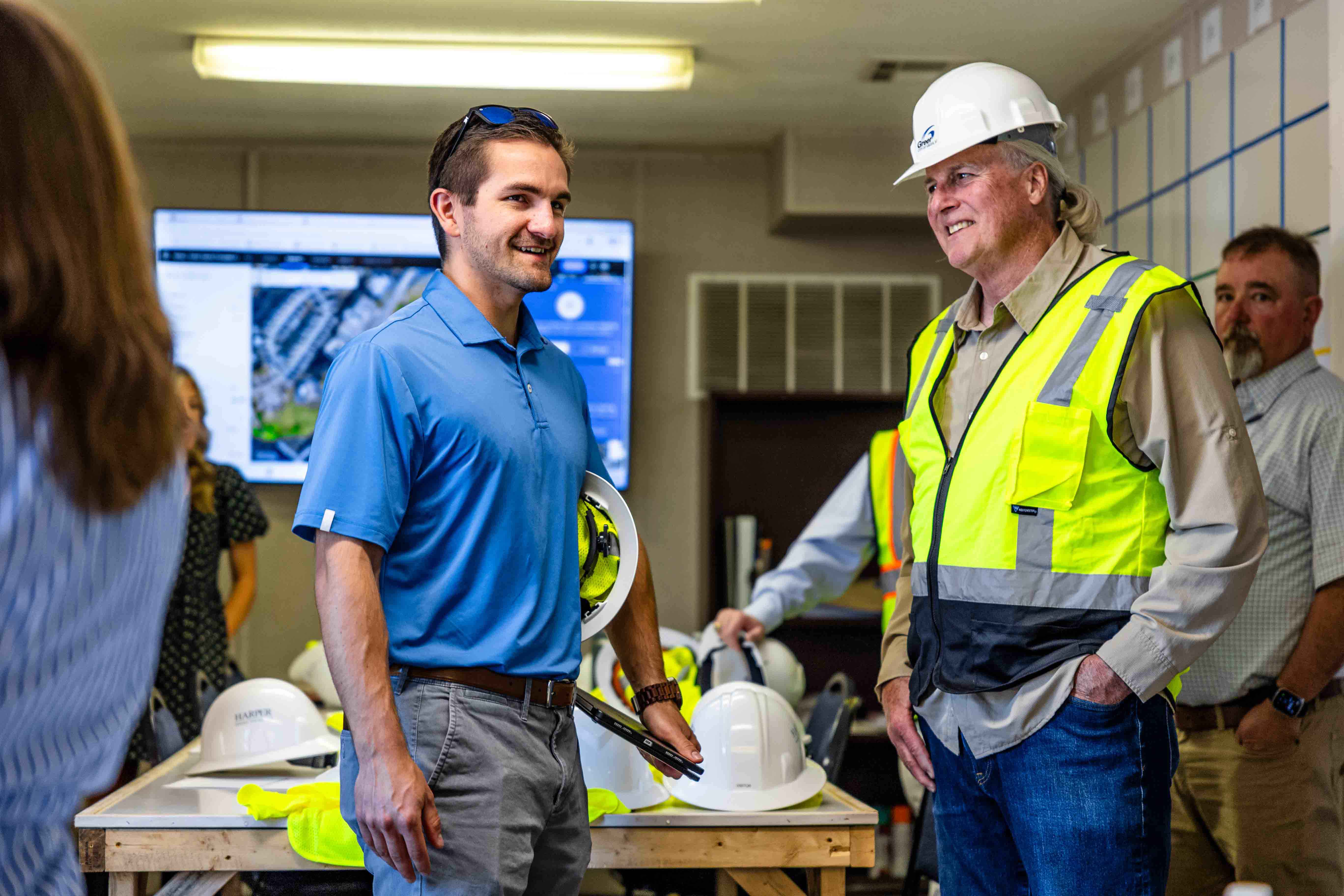 Two men talk and laugh inside a construction trailer