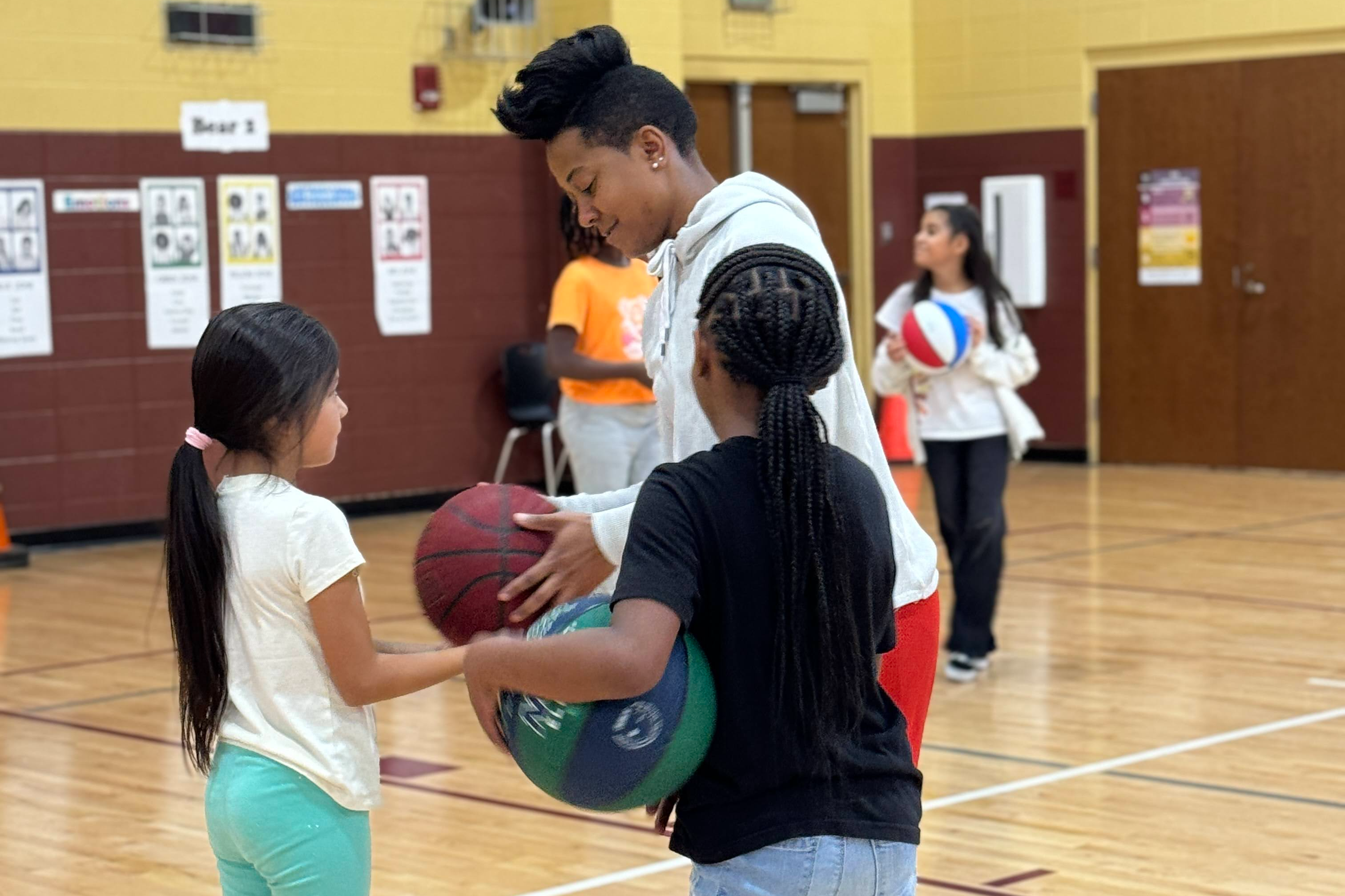 yeacher and two students holding basketballs