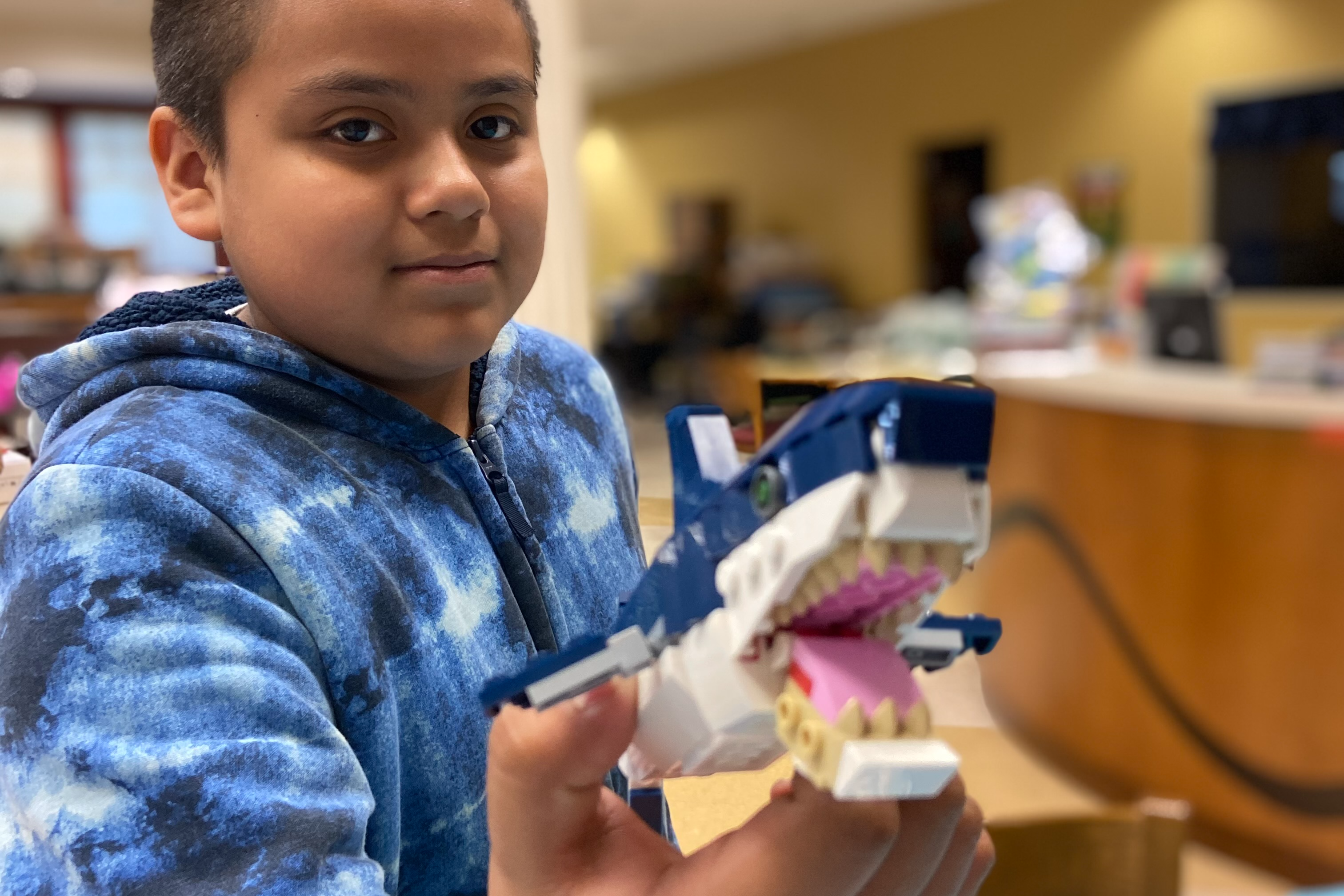 student holding up a shark made of Legos.