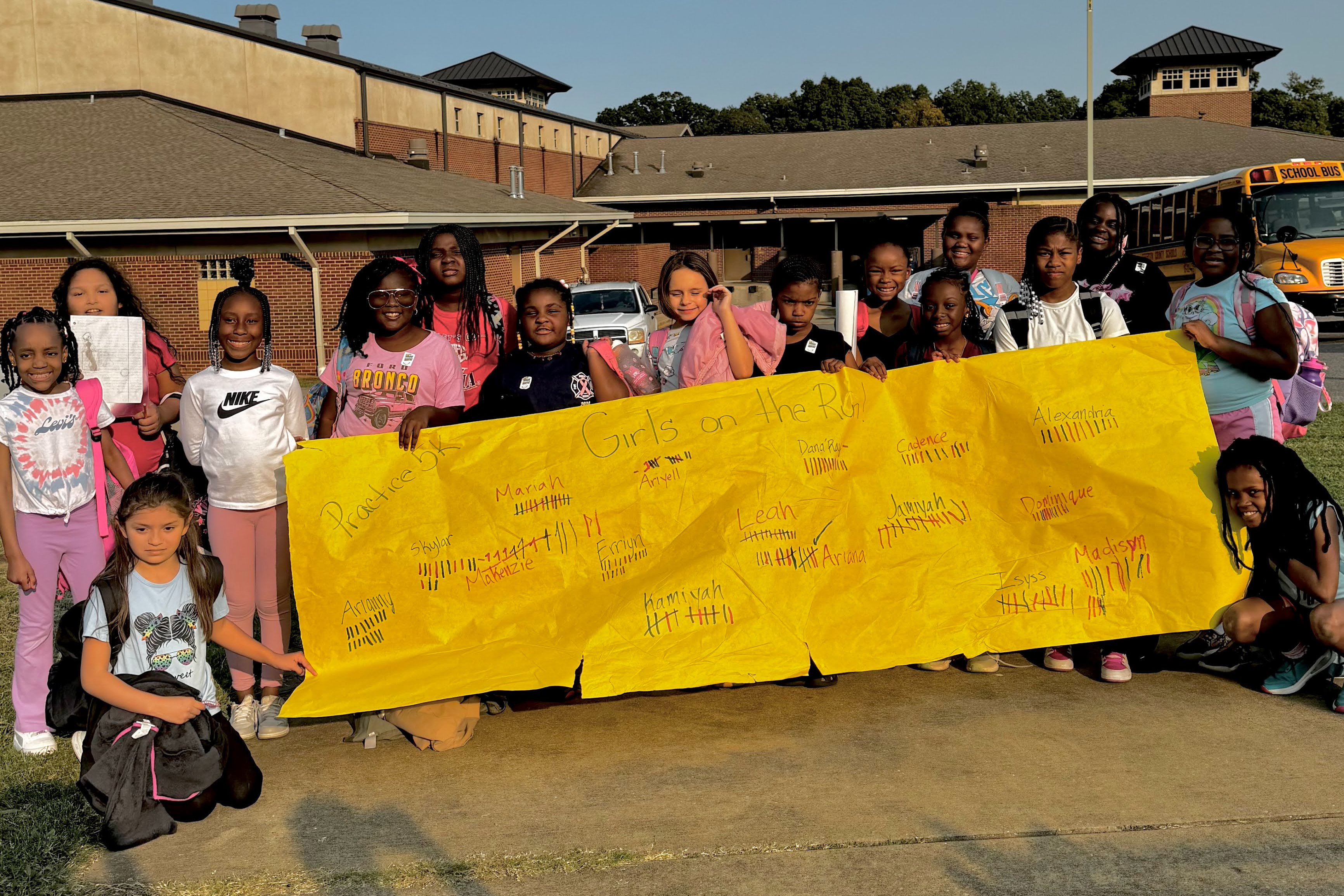 female students standing and holding a banner that has tally marks on it