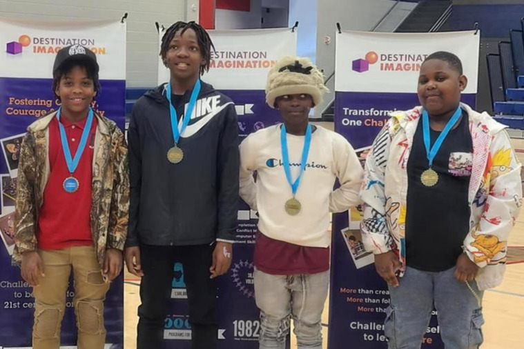 four students with medals around their necks standing and smiling