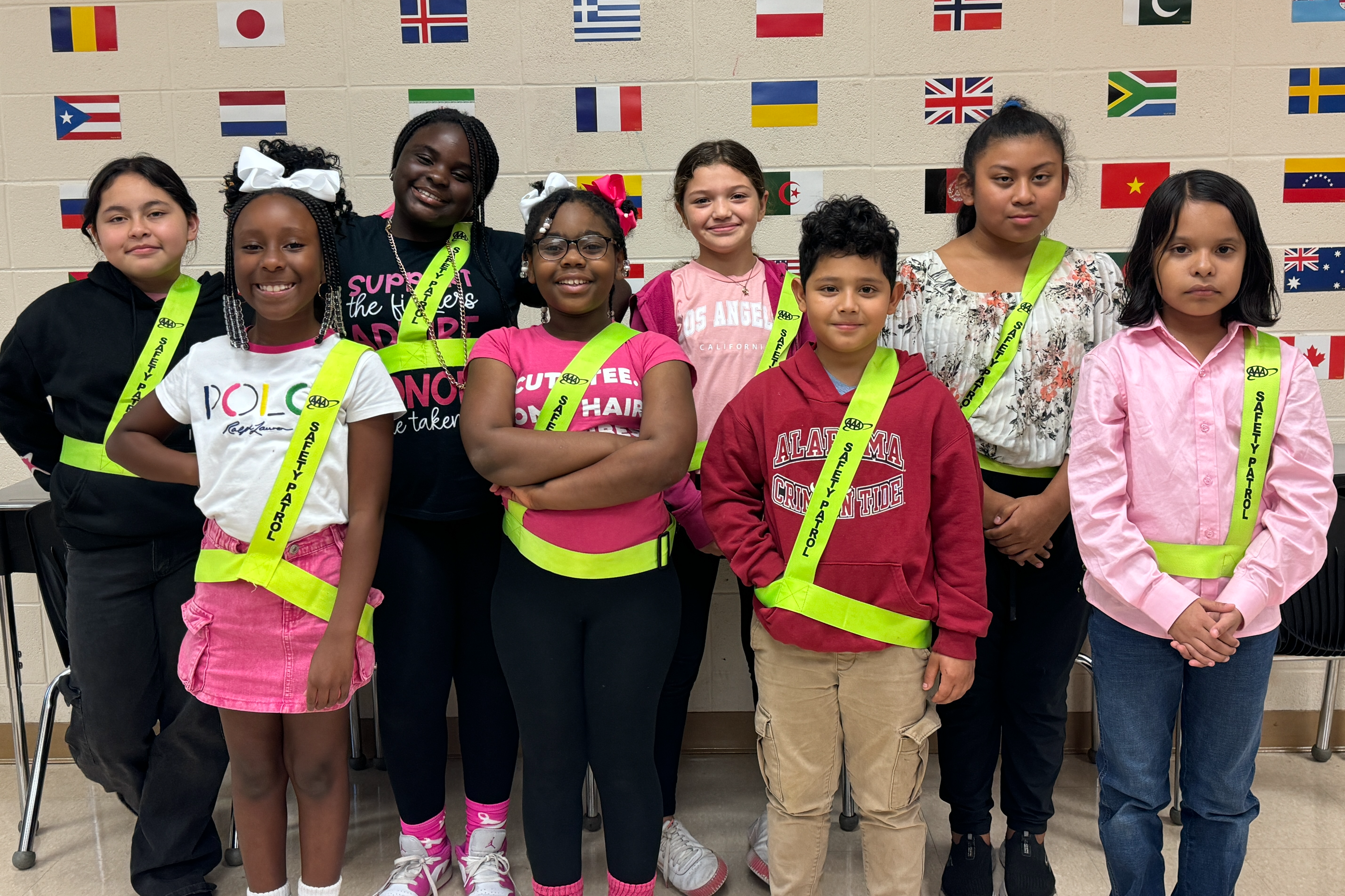 Group of 8 students wearing safety patrol sashes standing and smiling