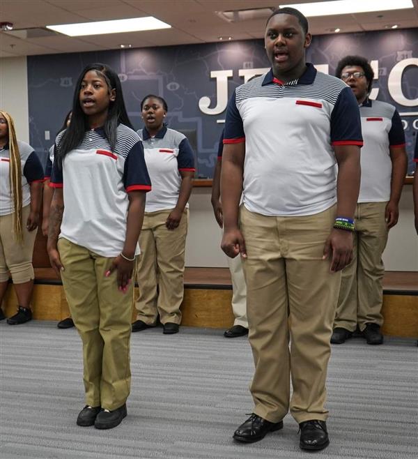 Two individuals wearing uniforms, standing together and looking forward.