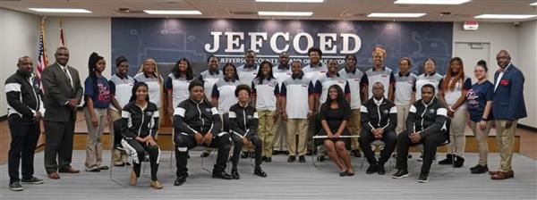 A group of people posing for a picture in front of a sign with the word 'JEFECED' on it.