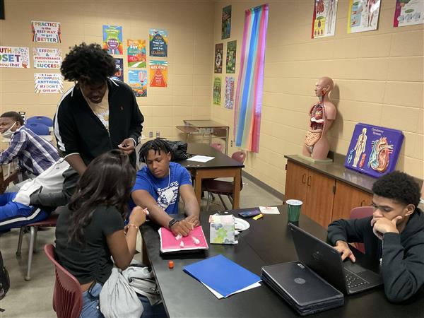 A group of young adults engaged in a collaborative learning activity at the front of a classroom.