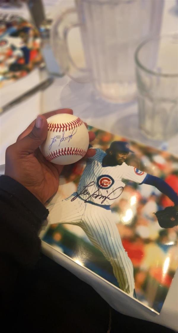 A signed baseball with a sports card in the background.