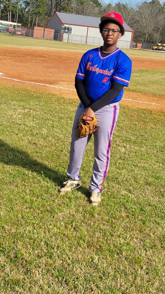 A young boy in a baseball uniform, standing on the field.