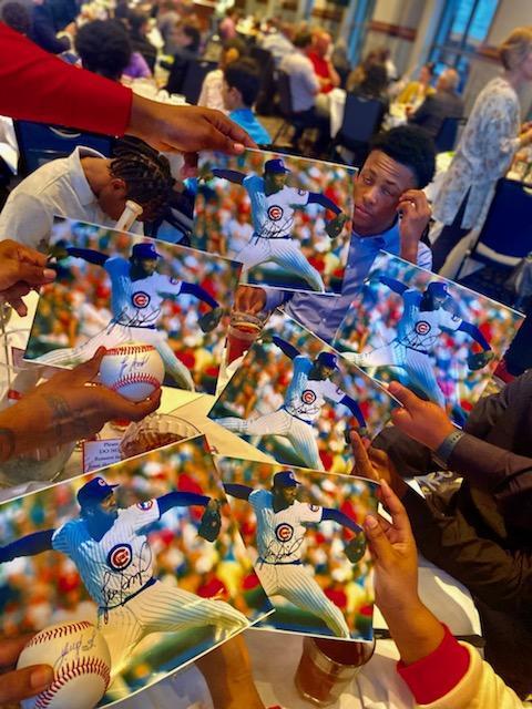 Several individuals displaying multiple copies of a baseball player's photo in their hands.