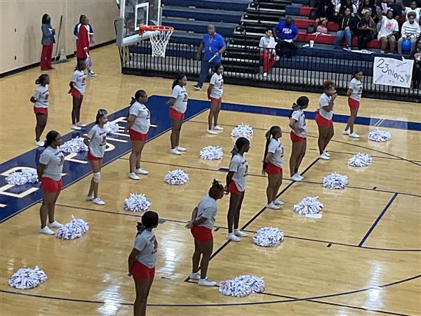 Line of cheerleaders in a gym, preparing for a performance.