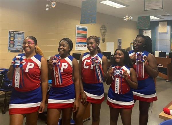 A group of cheerleaders posing in a classroom setting, wearing their uniforms with pride.