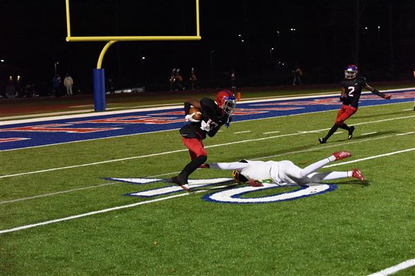 Football game in progress, with player lying on field after tackle.