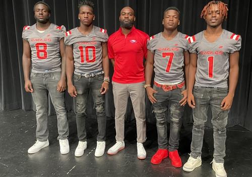 Football team posing with their coach on the field.