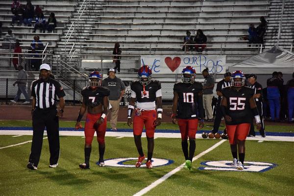 A group of football players in red uniforms standing on a field with their chest out, ready for action.