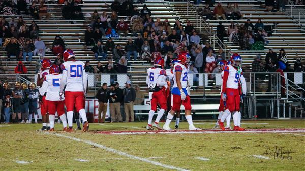 A group of football players gathered on a field after a game.