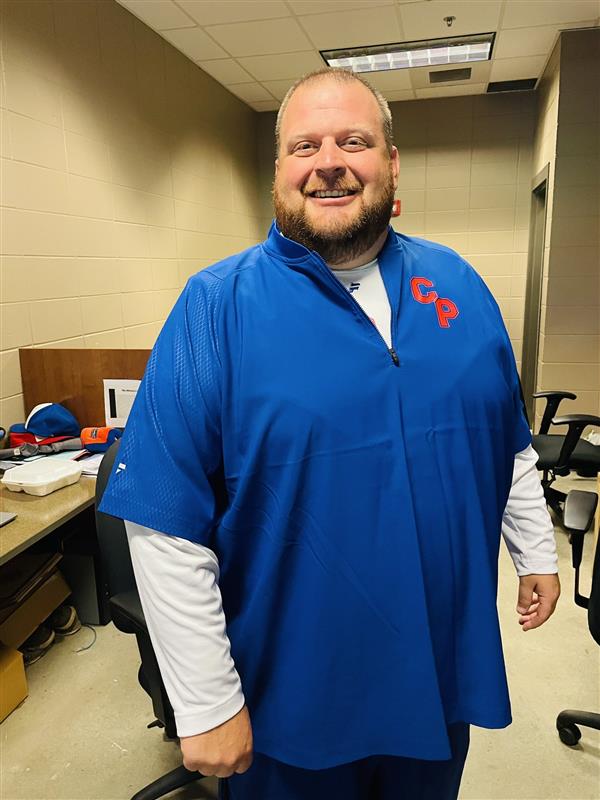 Man in blue and white shirt standing in room.