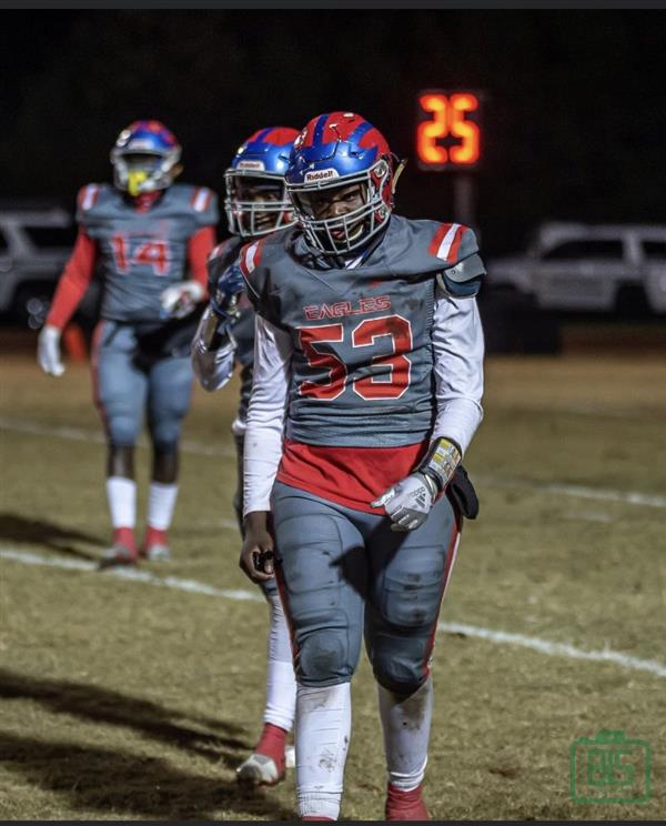 A football player wearing a jersey with the number 63, standing on a field during nighttime.