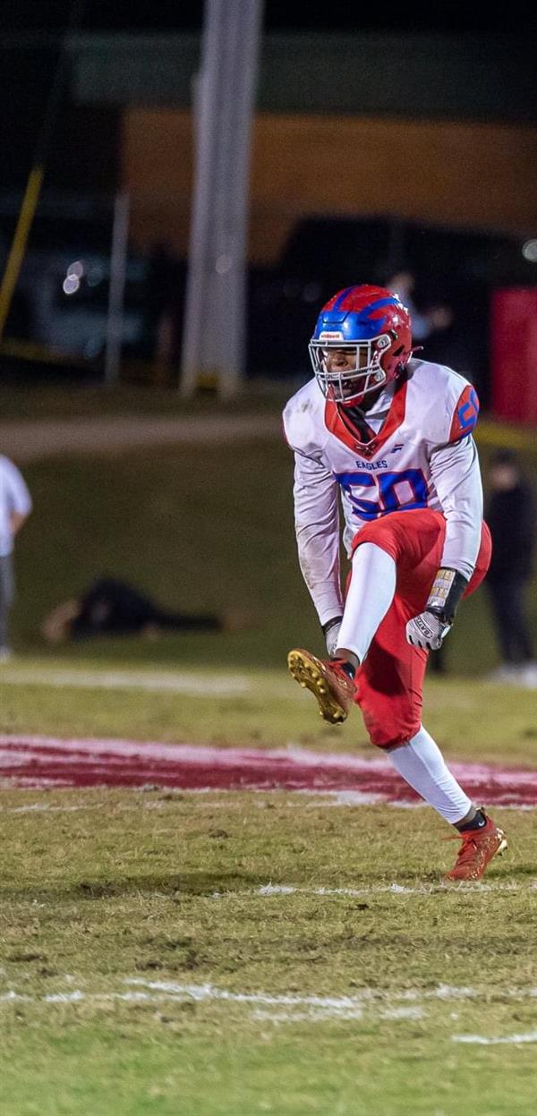 Football player in motion on the field, kicking a ball.