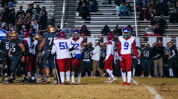 Group of athletes on field at nighttime during game.