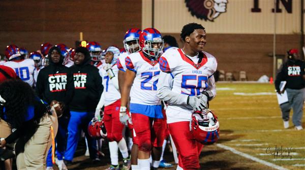 A group of football players in white and red uniforms on a field, standing together after a game.