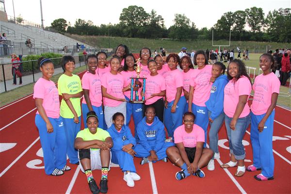 This is a group photo of a track and field team, posing proudly with their trophy.