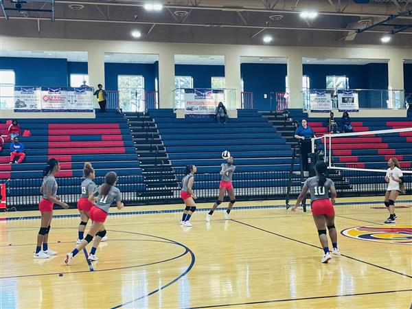 A group of female athletes in action during an indoor volleyball game.