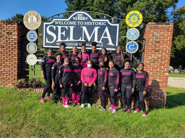 A group of athletes posing for a picture in front of a sign.