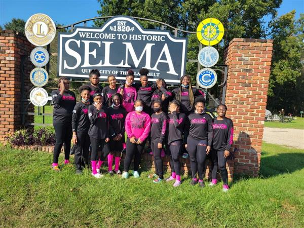 The team poses for a photo in front of the Selma sign.