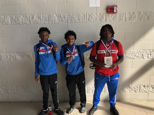 Three young athletes posing for a photo after receiving awards.