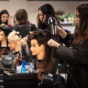 Students style the hair of mannequins