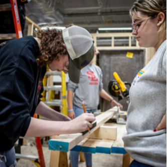 Students measure out boards on a sawhorse