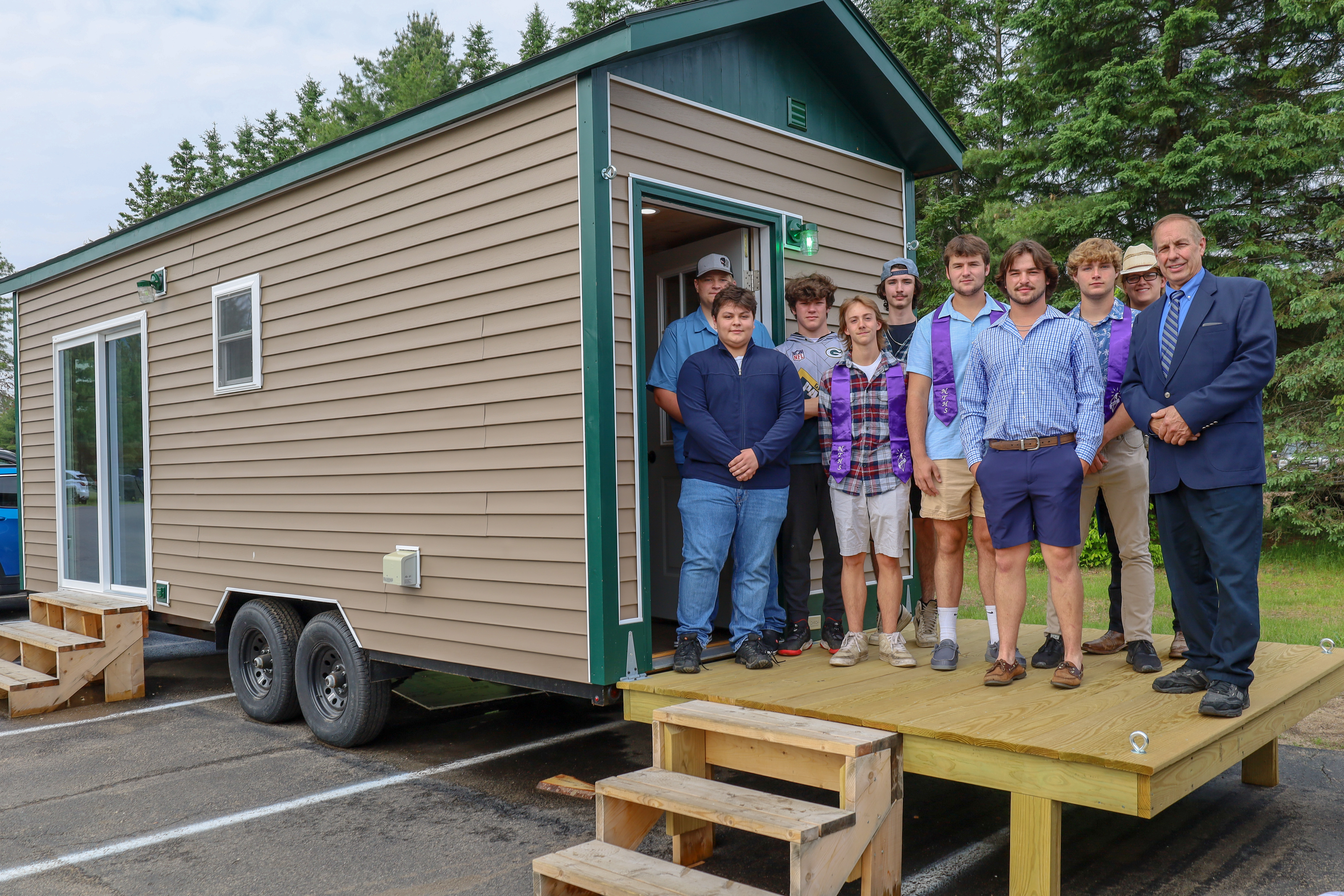A group of people poses on the porch of a tiny house