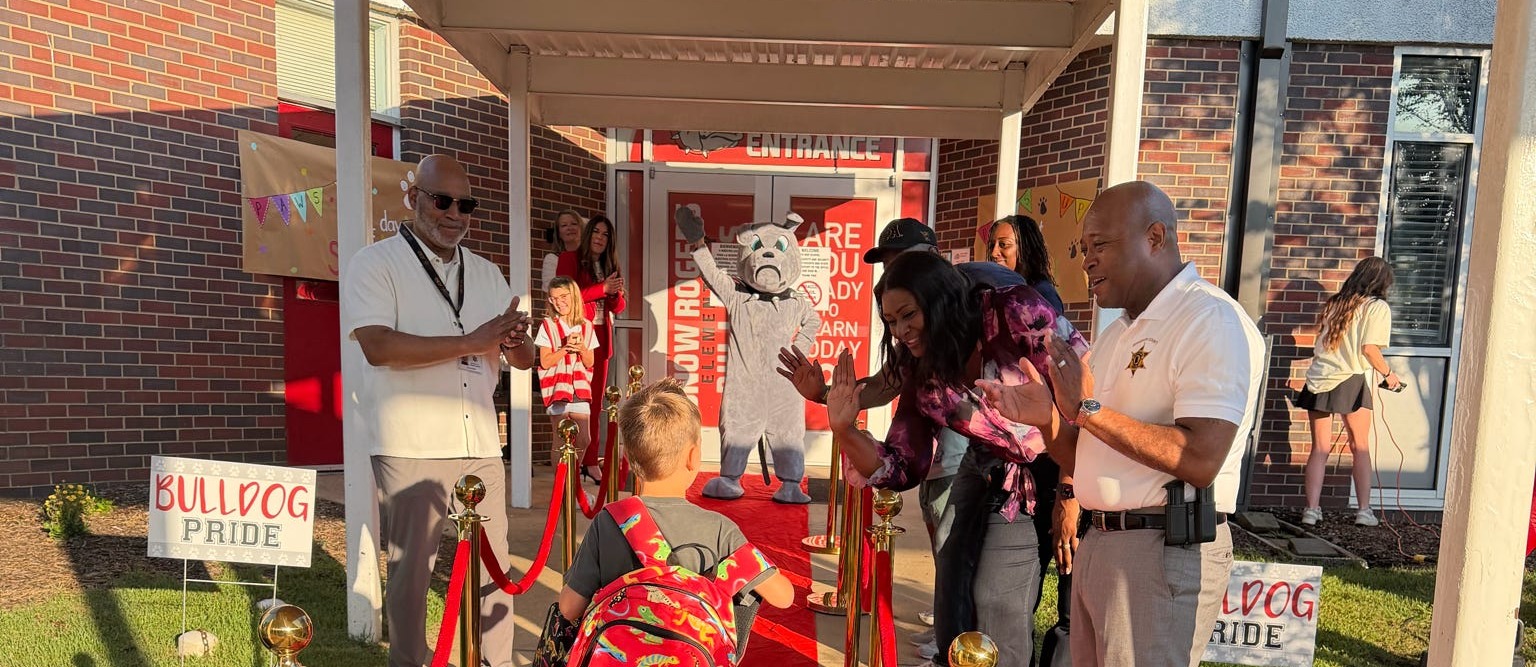 Student entering school doors on a red carpet