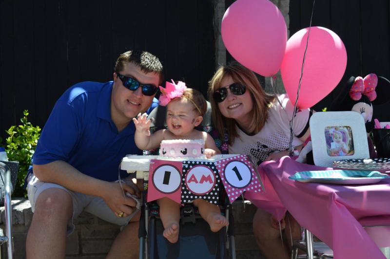 A couple sits in a chair, lovingly holding their baby girl