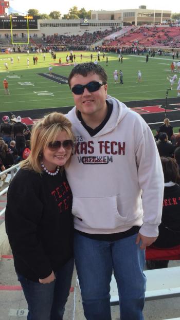 A man and woman smile together for a photo at a lively football game