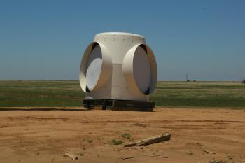 A large white object stands alone in the center of a green field