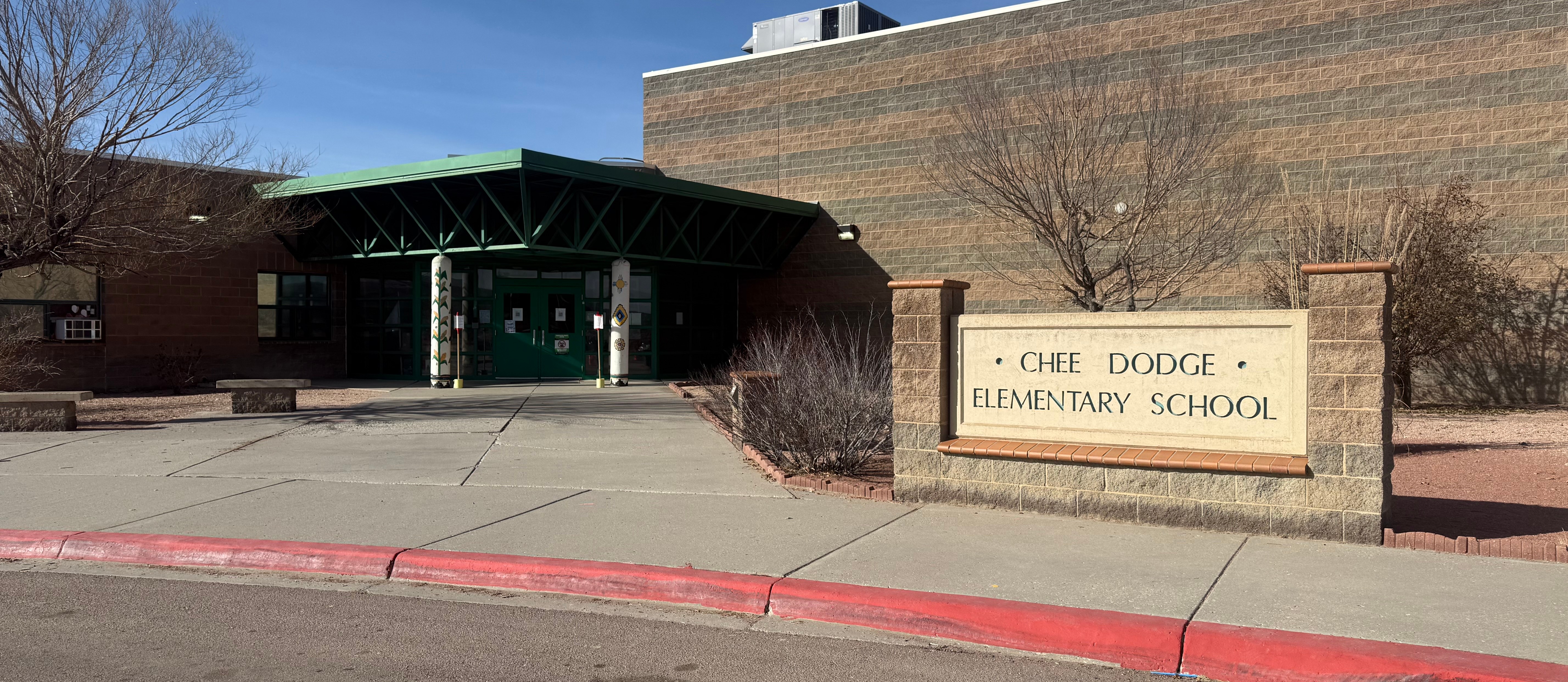 Chee Dodge Elementary front entrance with trees and sidewalk along with Chee Dodge sign 