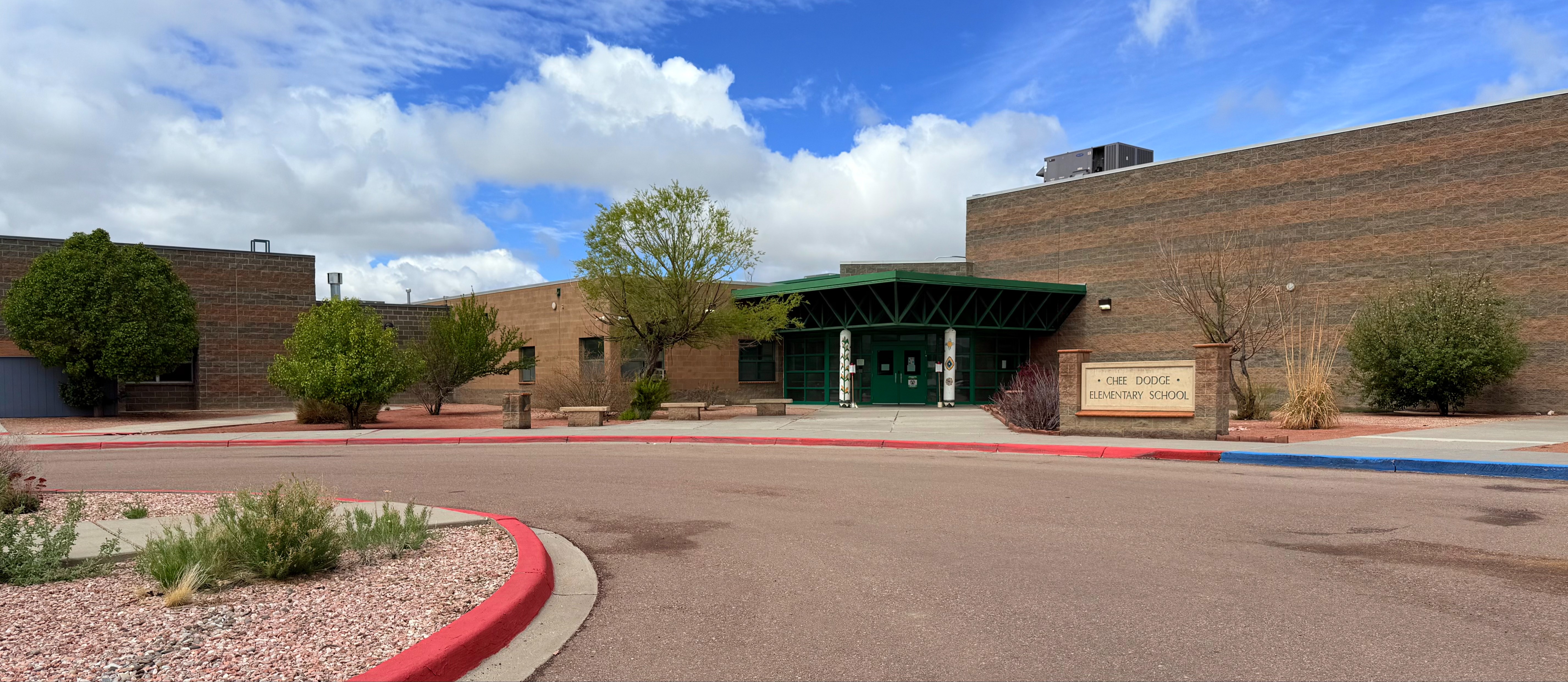 Chee Dodge Elementary front entrance with trees and sidewalk along with Chee Dodge sign 
