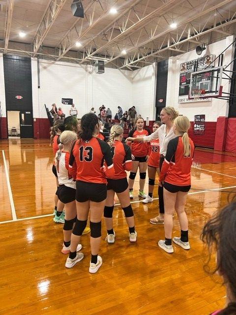 Girls' volleyball team posing for a photo on the court.